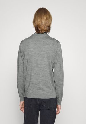 Suéter gris de manga larga, textura suave, puños y dobladillo acanalados, escote redondeado, sin patrones visibles. Llevado sobre jeans oscuros, visto por detrás.
