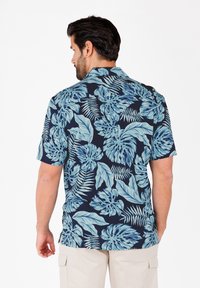 Korte mouwen shirt met een marineblauwe basis en grote lichtblauwe tropische bladpatronen. Gladde stof met een klassieke kraag en een losse fit.