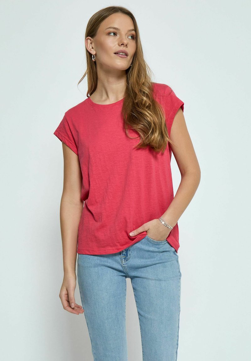 Kortärmad, rundhalst-t-shirt i en livlig rosa tyg. Slät textur, avslappnad passform, tillsammans med ljusblå jeans.