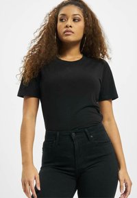 Svart kortermet t-skjorte med rund hals, kombinert med høyhalsede svarte jeans. Jevn tekstur, tettsittende design, minimalistisk stil.