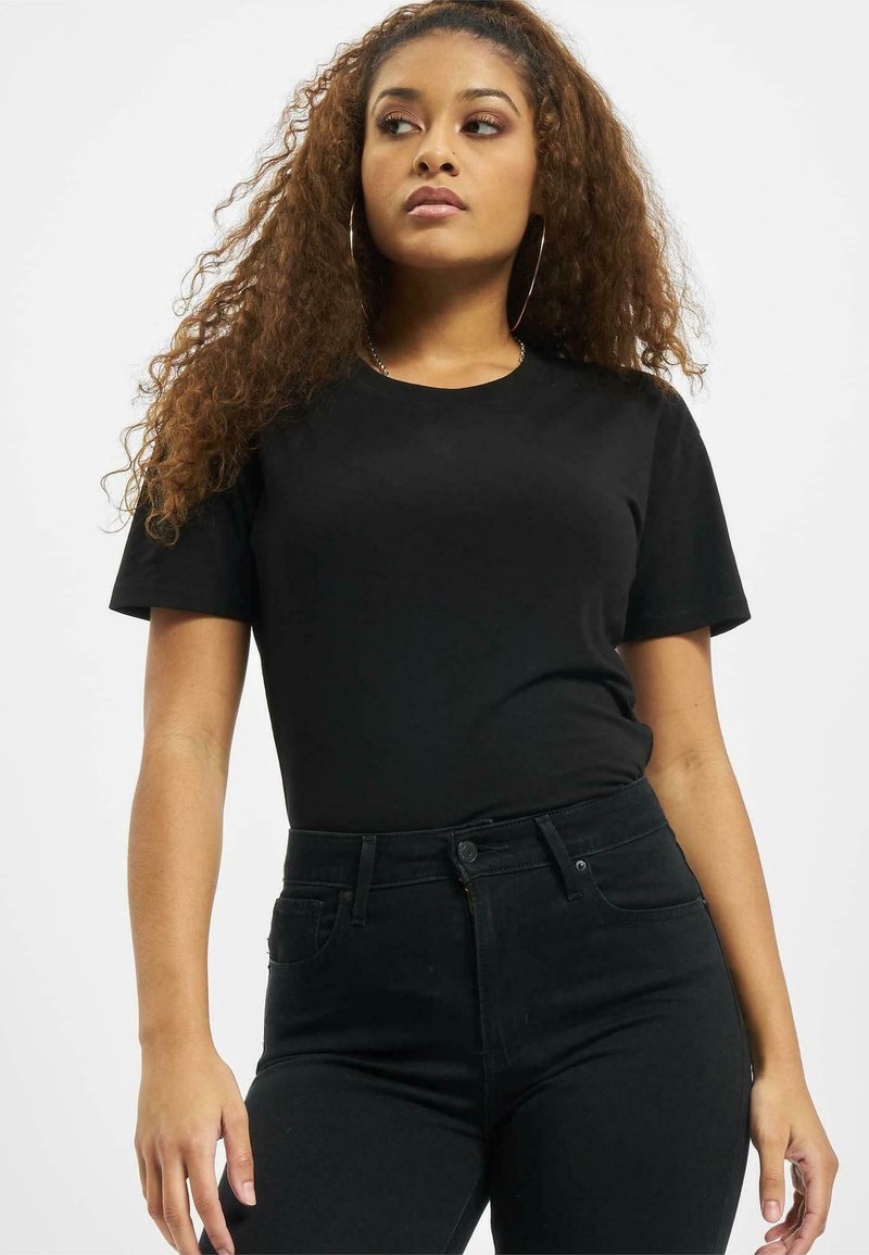 Svart kortermet t-skjorte med rund hals, kombinert med høyhalsede svarte jeans. Jevn tekstur, tettsittende design, minimalistisk stil.