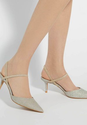 Talons aiguilles en argent métallique avec une finition texturée. Dotés de fines brides de cheville croisées à l'arrière et d'un talon stiletto effilé.