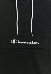 Felpa nera con zip e dettagli bianchi. Presenta un logo ricamato sul petto, cappuccio con coulisse e una texture liscia.