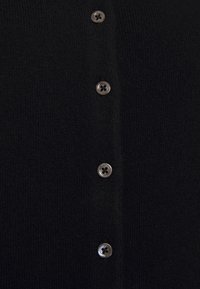 Cardigan nero con tessuto a maglia strutturato e sei bottoni in tonalità argento lungo il davanti, dettagli di cuciture visibili.