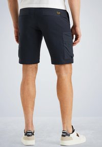Donkerblauwe cargoshorts met opgestikte zakken, een gladde textuur en een aansluitend ontwerp, gezien van achteren met lichtgekleurde sneakers.