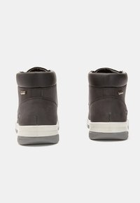 Zapatillas altas de cuero gris oscuro con una textura suave, que cuentan con un cuello acolchado y suelas de goma blancas con patrones de tracción grises.
