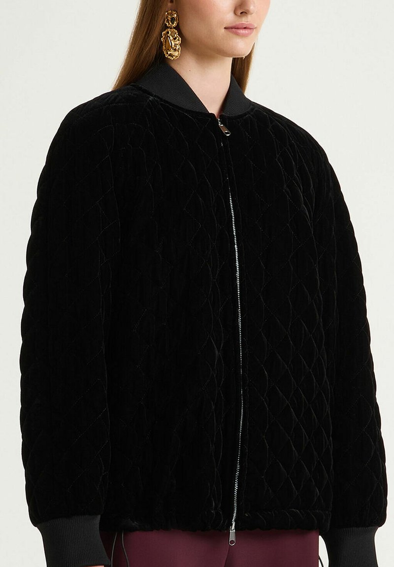 Bomber nero trapuntato in tessuto morbido, con cerniera frontale, polsini e colletto a costine; superficie con motivo a diamante.