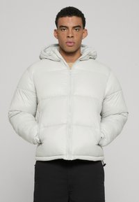 Gai pelēks pūkains jaka ar rāvējslēdzēju un kapuci. Iemīloto da�ļu ar pāršūtiem ikriem un elastīgām piedurknēm, lai nodrošinātu ciešu piegulšanu. Gluda, spīdīga auduma tekstūra.