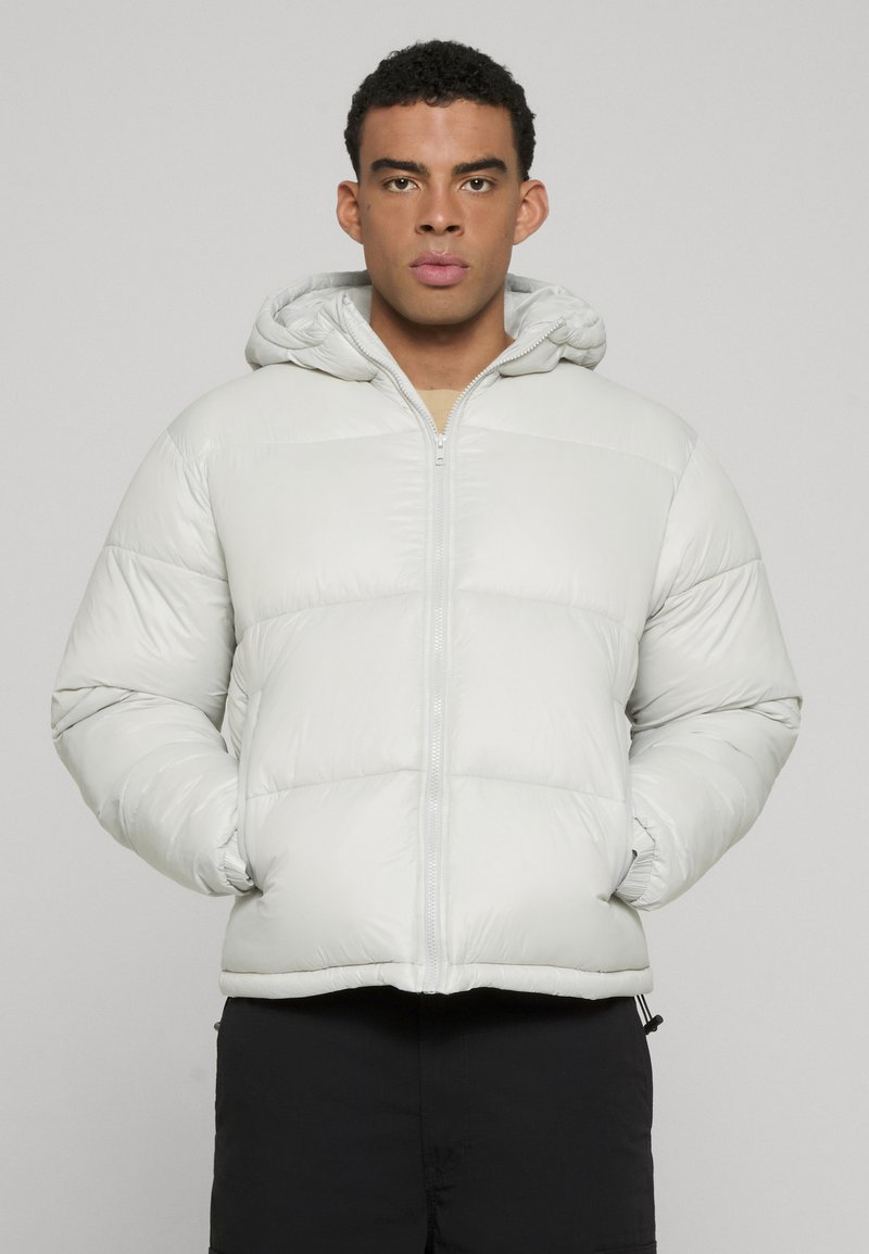 Gai pelēks pūkains jaka ar rāvējslēdzēju un kapuci. Iemīloto daļu ar pāršūtiem ikriem un elastīgām piedurknēm, lai nodrošinātu ciešu piegulšanu. Gluda, spīdīga auduma tekstūra.