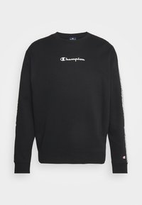 Svart sweatshirt gjord av bomullsmix, med en vit "Champion"-logotyp på bröstet och kontrasterande detaljer längs ärmarna.