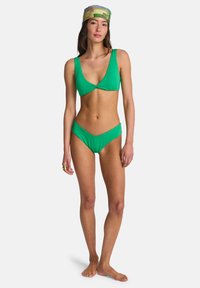 Πράσινο μπικίνι δύο τεμαχίων με τριγωνικό τοπ που έχει λεπτομέρεια στριφώματος και εσώρουχα μεσαίας μέσης, φτιαγμένο από λείο, ελαστικό ύφασμα.
