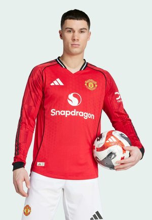 Rotes Longsleeve-Fußballtrikot mit V-Ausschnitt, schwarzen Akzenten und gemusterten Ärmeln. Das Logo und der Markenname sind auffällig platziert.