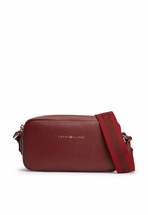 Sac bandoulière rectangulaire en cuir rouge foncé avec fermeture éclair dorée et large bandoulière rouge ajustable brodée du nom de la marque.