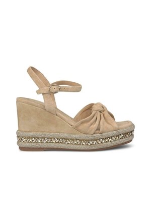 Beige suede wedge sandals with ankle strap, knotted front design, and decorative metallic trim featuring small gemstones along the sole.