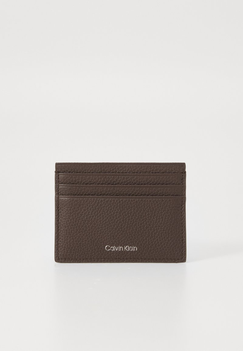 Portofel de piele maro cu textură de pietricele, având trei sloturi pentru carduri și logo-ul Calvin Klein embosat în argintiu în centrul frontal.