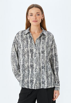 Camisa de manga larga en estampado de serpiente en blanco y negro. Con cuello, frontal abotonado y un ajuste holgado con textura suave.