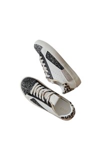 Baskets blanches avec des accents noirs pailletés, un talon en imprimé léopard, une surface texturée et des lacets crème. Présente un design moderne et des détails perforés.