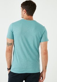 Tamsiai mėlynas trumpa rankovė t-shirt pagaminta iš minkštos, tekstūruotos medžiagos. Turi klasikį apvalų kaklą ir subtilų heather tipo raštą nugaroje.
