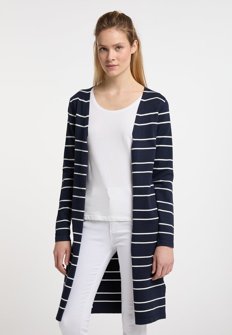Cardigan blu navy con righe orizzontali bianche, apertura frontale, maniche lunghe e design a lunghezza intermedia, indossato sopra una maglietta bianca semplice.
