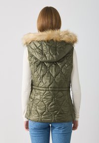 Quilted olive green vest with a faux fur hood, featuring a fitted waist and textured pattern. Back view shows horizontal seam details.