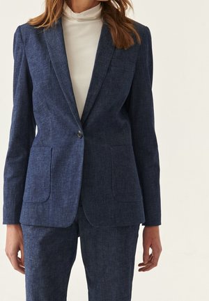 Blazer ajusté bleu marine en tissu texturé. Doté d'une fermeture à un bouton, de revers crantés et de deux poches avant.