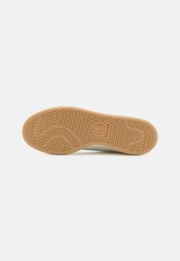 Bežna guma s rupičastim uzorkom u obliku saća s valovitim dizajnom i utisnutim logotipom. Čiste linije i minimalni detalji.