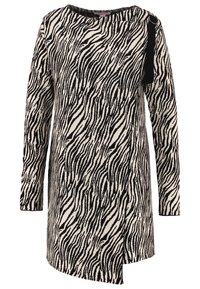 Randig stickad klänning i svart och kräm, med långa ärmar, rund halsringning och en asymmetrisk fåll med en dekorativ detalj.