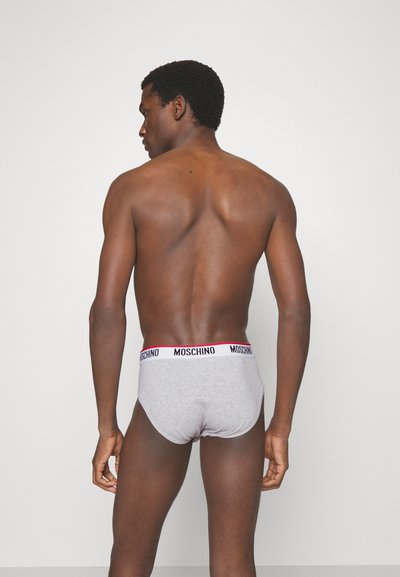 Boxer gris avec une ceinture Moschino rouge et noire. Le tissu semble doux et extensible, épousant étroitement le corps. Pas de motifs ou de designs visibles.