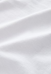 Tela de algodón blanca con una textura suave, que presenta sutiles arrugas y una superficie lisa y uniforme. Sin patrones ni acentos visibles.