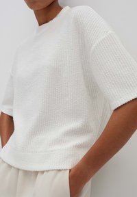 Witte getextureerde short-sleeve top met een ronde halslijn en een subtiel ribbelpatroon, ontworpen met een relaxte fit en een cropped silhouet.