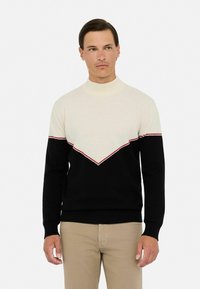 Strickpullover mit hohem Kragen, cremfarbener oberer Hälfte, schwarzer unterer Hälfte und einem rot-gestreiften Zickzackmuster über der Brust.