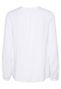Hvid langærmet skjorte med rund halsudskæring, samlet detaljering på ryggen og tætsiddende manchetter. Stoffet ser blødt og let ud.