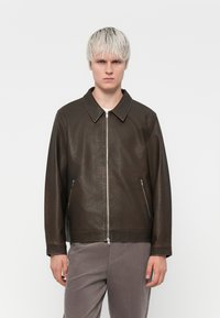 Chaqueta de cuero marrón con un cuello clásico, cierre de cremallera y bolsillos laterales, que presenta un acabado texturizado y mangas largas.