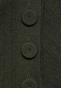 Dunkelgrüner, gestrickter Pullover mit vier strukturierten Knöpfen, der ein weiches und glattes Stoffgefühl vermittelt. Vertikales Rippmuster ist sichtbar.