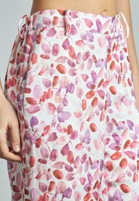 Bloemige broek met een aquarel bladpatroon in tinten van roze en paars, met een witte achtergrond en een strikbandje aan de taille.