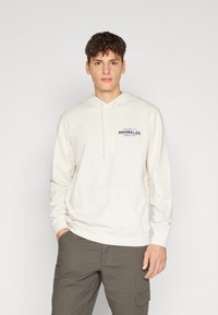 Felpa crema con tasca frontale, cordini e piccolo logo testuale blu "Wrangler" sul petto; design semplice e texture morbida.