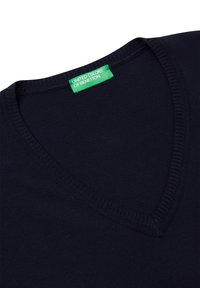 Námorní svetr s V-výstřihem vyrobený z měkkého materiálu, který má žebrovaný výstřih. Vnitřní štítek je zelený s textem "United Colors of Benetton".