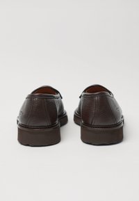 Bruine leren schoenen met een gestructureerde afwerking, ronde neus en een lage rubberen zool, voorzien van stikseldetails en een gladde binnenvoering.