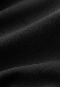 Schwarzer Stoff mit einer glatten, strukturierten Oberfläche, die subtile Muster aufweist. Das Material wirkt leicht und fällt fließend.