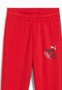 Pantaloni da tuta rossi con elastico in vita, caratterizzati da un logo Puma nero e una grafica. Realizzati in un tessuto morbido e testurizzato.
