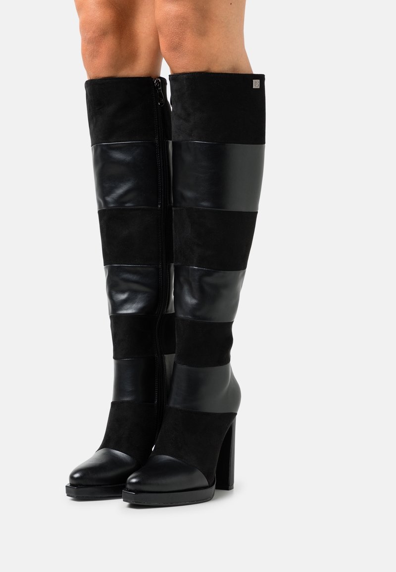 Stivali neri al ginocchio con tacco, caratterizzati da un mix di camoscio e pelle lucida in pannelli orizzontali, con cerniera laterale e punta arrotondata.