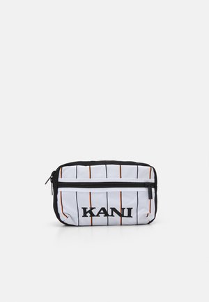 Pochette blanche avec des rayures verticales noires et orange, dotée d'une fermeture éclair supérieure et du logo « KANI » en noir. Surface en tissu texturé.