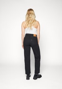 Svarta högmidjade jeans med rak benform, med en brun läderlapp bak i midjan och bakfickor. Slät denimtextur.