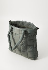 Sac fourre-tout matelassé en vert pastel, avec fermeture éclair, deux anses en tissu et un extérieur doux et rembourré avec un motif géométrique.