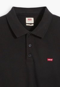 Czarny polo wykonany z bawełny, z strukturalnym kołnierzykiem, trzema guzikami z przodu i małym czerwonym logo Levi's na klatce piersiowej.
