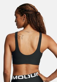 Svart ribbad sportbh med en scoopback-design och breda axelremmar. Har en slät yta och minimal branding på midjebandet.