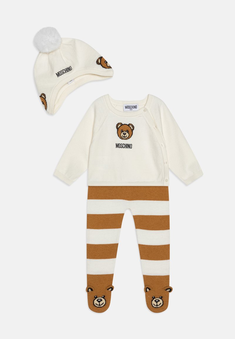 Maglione crema con grafica di un orso, pantaloni a righe marroni e crema abbinati con facce di orso sui piedi, completati da un berretto con pom-pom.