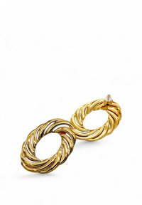 Orecchini pendenti in tono dorato con un design ovale ritorto, caratterizzati da una texture liscia e lucida e un centro aperto, fissati con un piccolo perno sul retro.