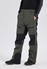 Waterdichte cargobroeken in groen en zwart. Kenmerken zijn onder andere ritszakken, versterkte knieën en een losse pasvorm voor comfort.