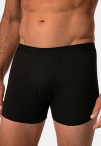 Černé bavlněné boxerky s měkkým elastickým pasem, na kterém je v jemném tónovém potisku uvedeno jméno značky "JP1880". Úzký střih.